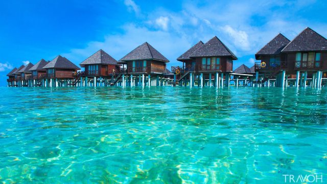 Resort units above shallow turquoise waters in the Maldives