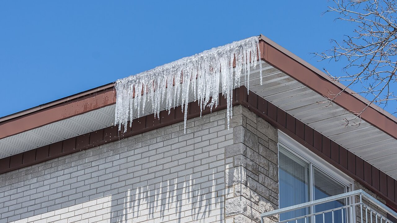 A thick fringe of icicles along the eaves usually means meltwater is refreezing at the roof edge, the classic start of an ice dam. Photo: Wilfredor, Wikimedia Commons, CC0.
